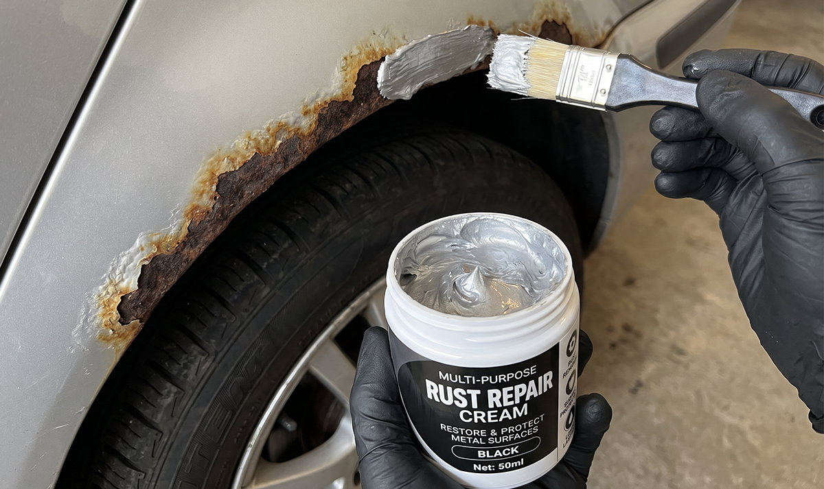 Rust repair cream application on car wheel arch